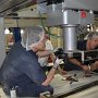JULY – Honorable Mention - Robot Repair<br />Stéphane Champagne, Local Lodge 2727, Kraft Canada, Montreal, QC<br />Mechanics René Palin and Remi Garon change a robotic arm on production equipment.<br />
